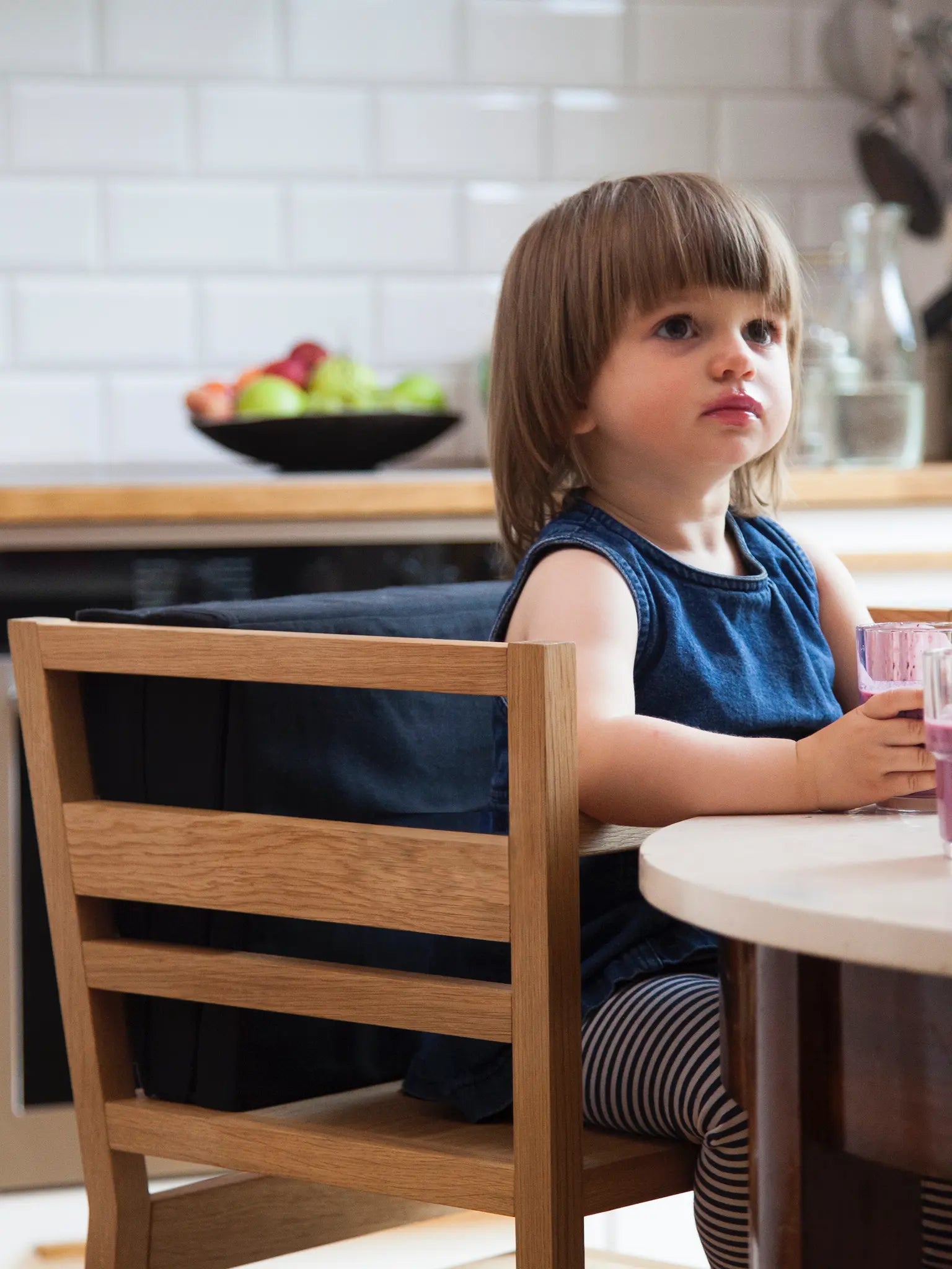Der ZAUNKÖNIG® Lernturm als Hochstuhl mit Kind am Küchentisch.
