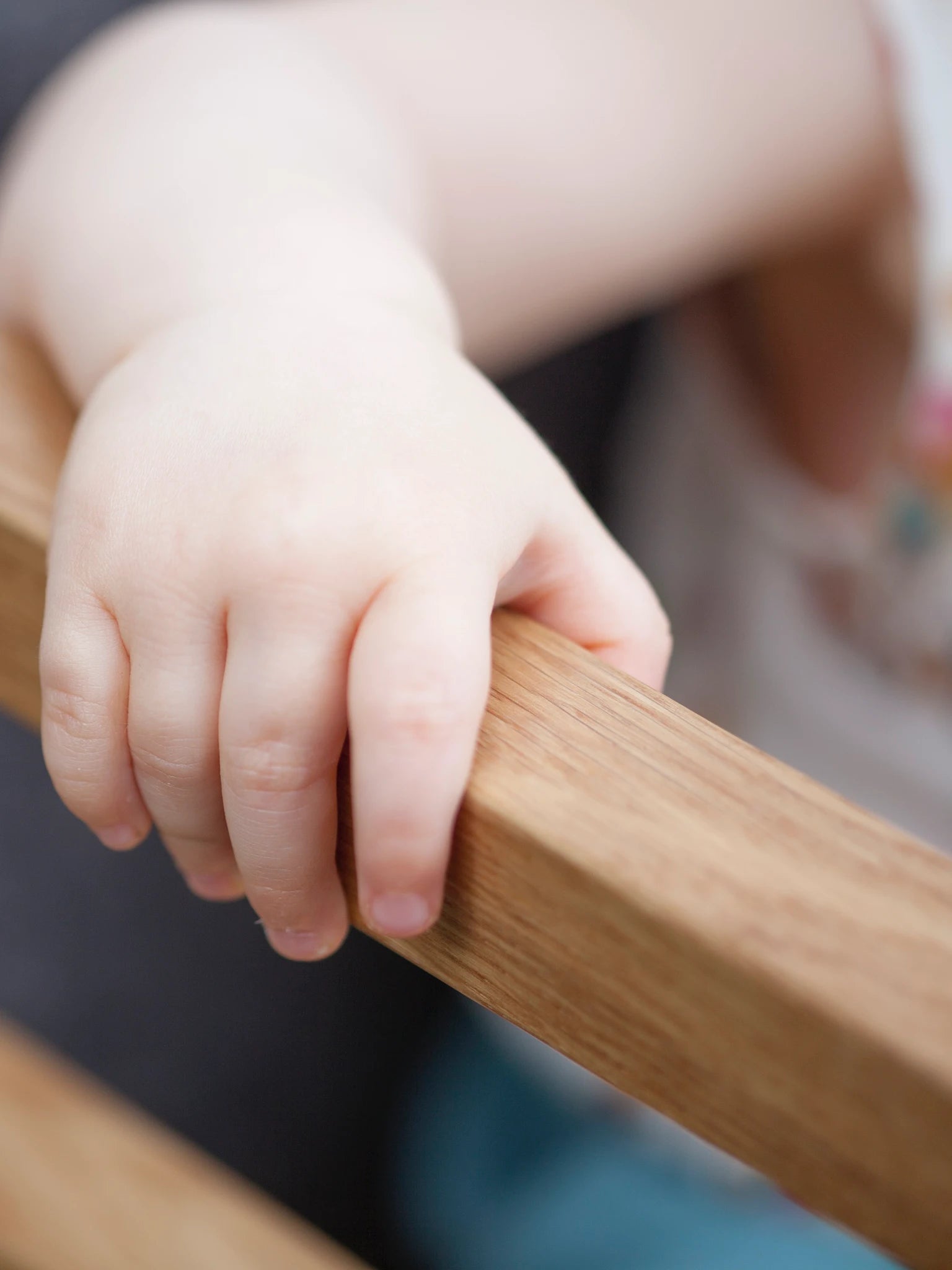 Der ZAUNKÖNIG Lernturm (3-in-1) aus massivem Eichenholz als Hochstuhl, Detailansicht mit Kinderhand.