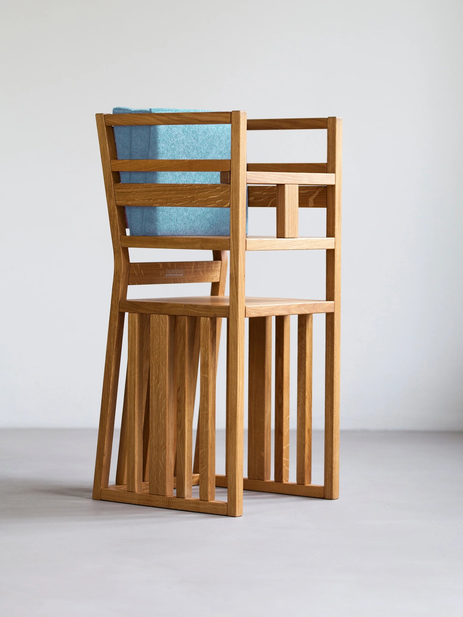 Der ZAUNKÖNIG Lernturm (3-in-1) als Hochstuhl aus massivem Eichenholz mit Schritthalterung für Kinder und Faltpolster aus Wollfilz in der Farbe Mint.