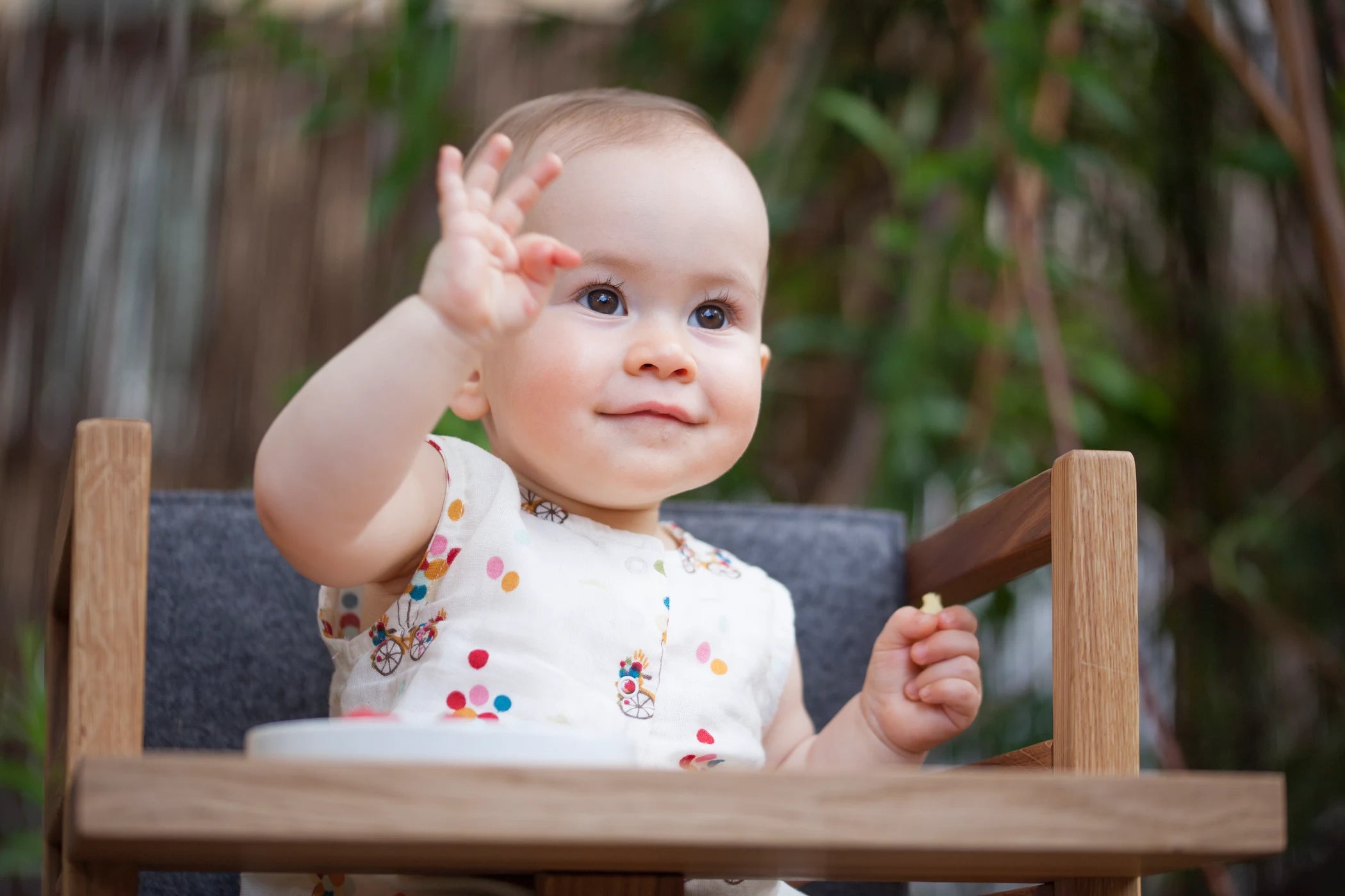 Der ZAUNKÖNIG Lernturm (3-in-1) aus massivem Eichenholz als Hochstuhl mit Kind im Garten.