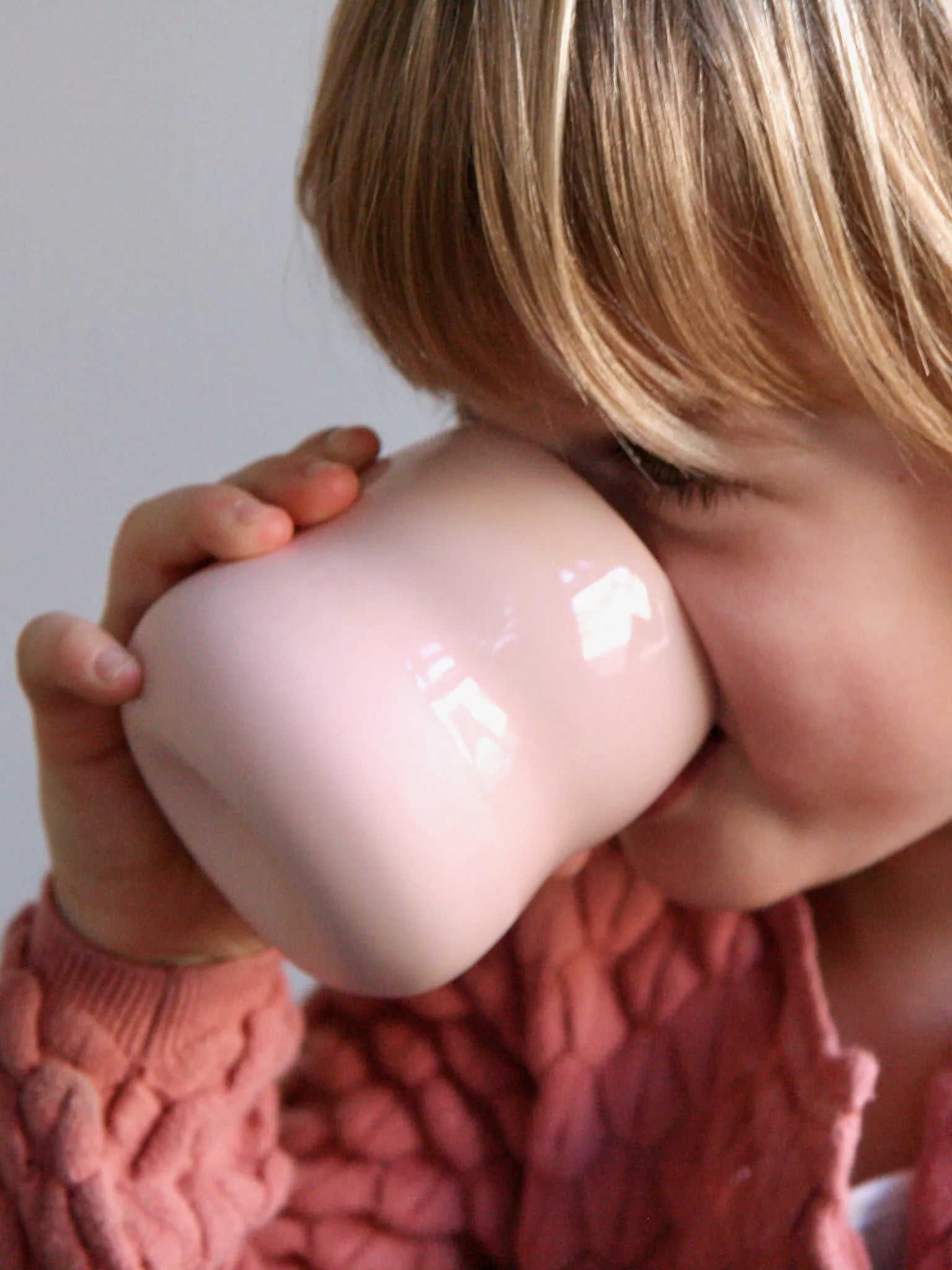 Kind mit Becher aus Porzellan in der Farbe Rosé, Detailansicht.