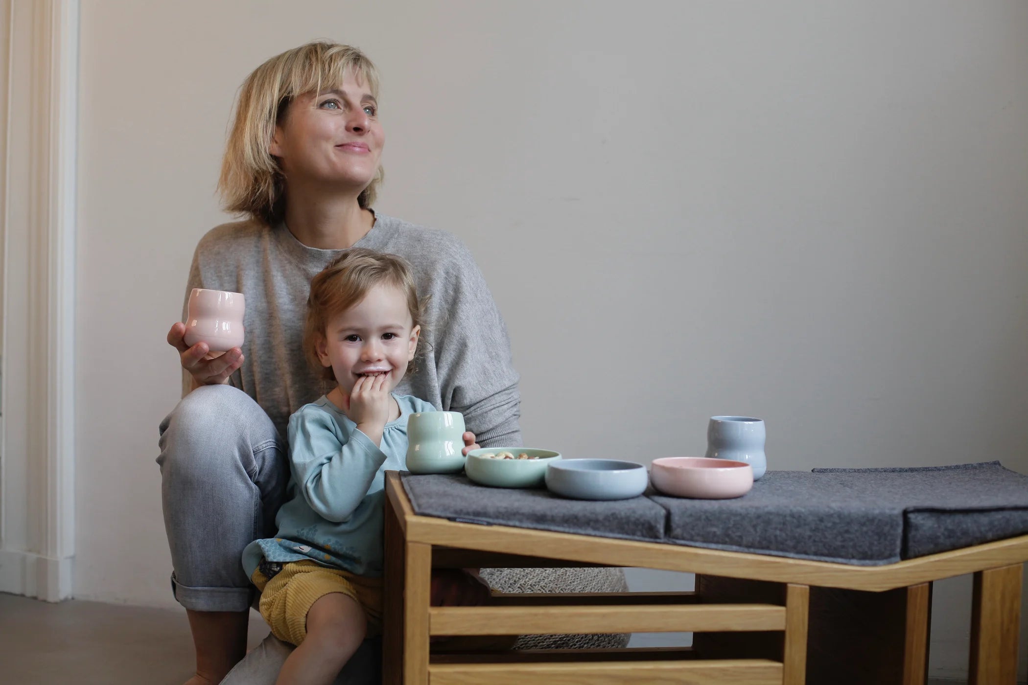 Kind und Mutter mit Kindergeschirr aus Porzellan in den Farben Agave, Rosé und Kornblume.
