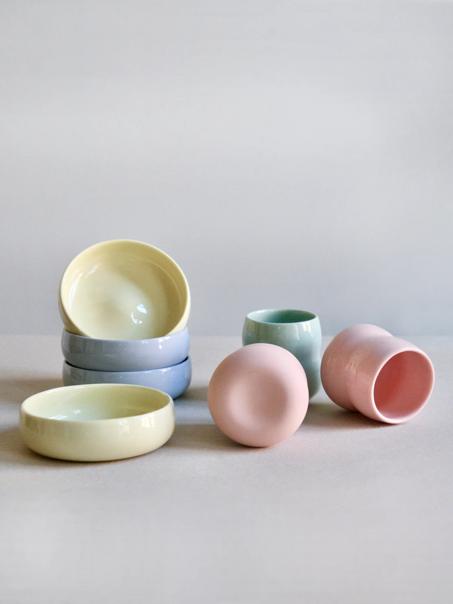 Das ZAUNKÖNIG Kindergeschirr aus Porzellan; Kinderbecher und Kinderschalen in den Farben Rosé, Limone, Agave und Kornblume.