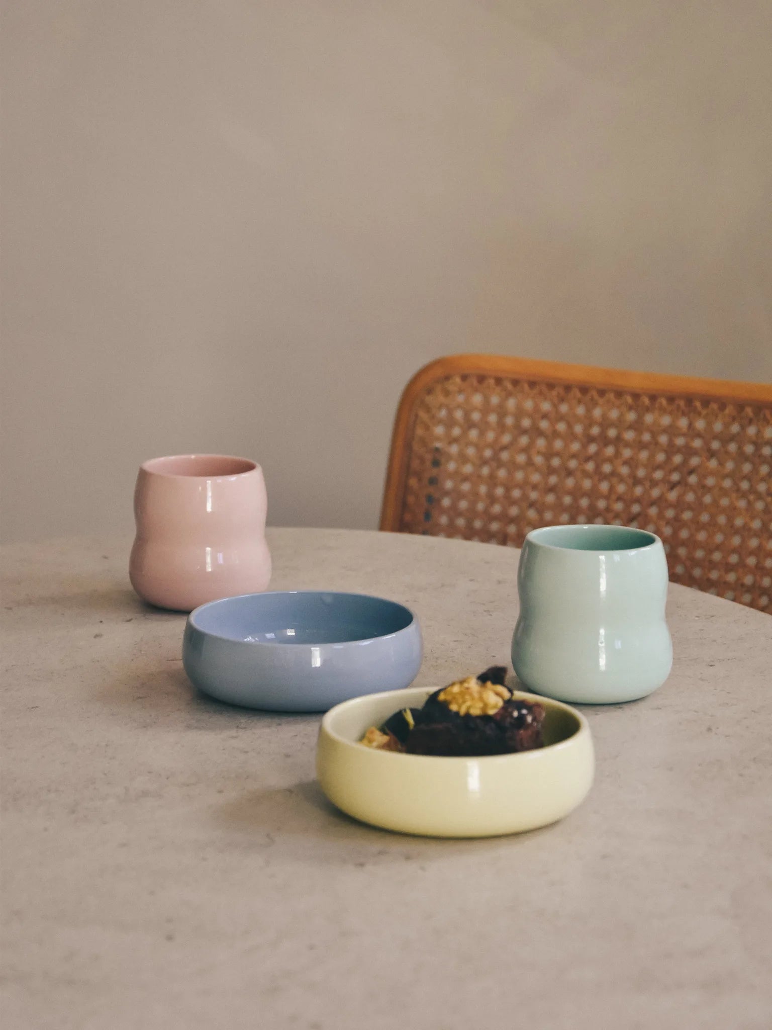 Kindergeschirr aus Porzellan auf dem Tisch der Familie; Kinderbecher in der Farbe Rosé und Agave mit Schalen in Kornblume und Limone.