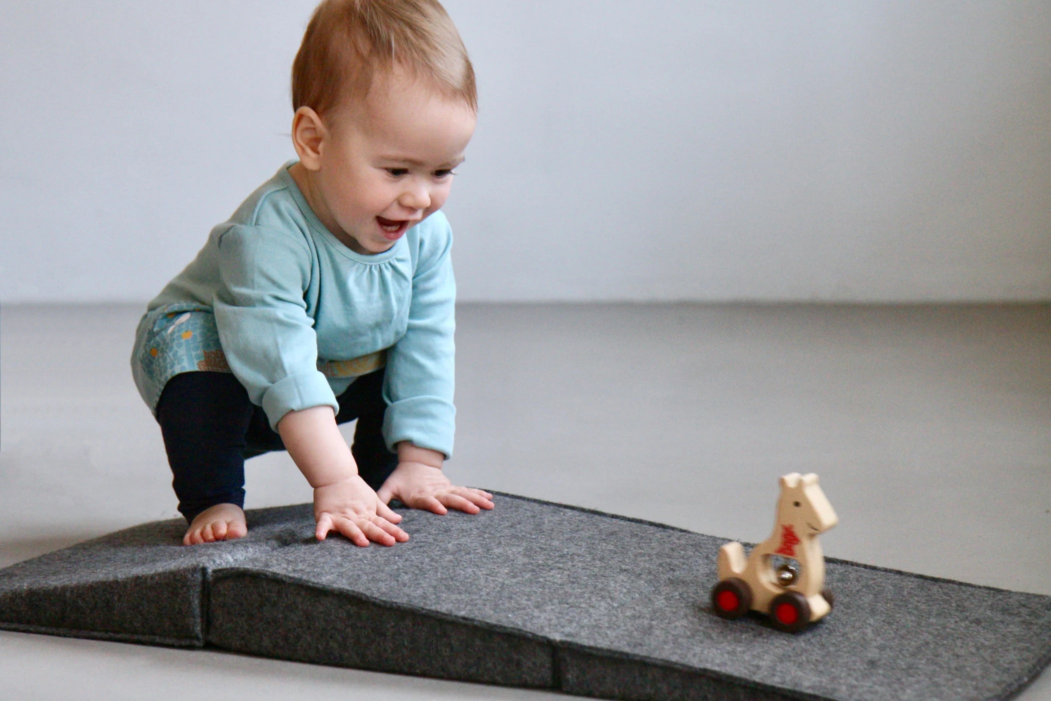 Kind spielt auf Faltpolster aus Wollfilz in der Farbe Elephant Grey.