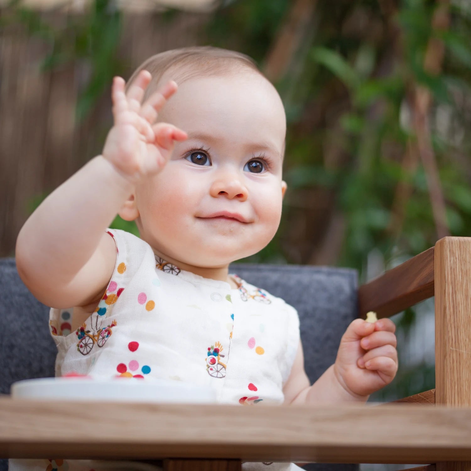 Der ZAUNKÖNIG Lernturm (3-in-1) aus massivem Eichenholz als Hochstuhl im Garten, Detailansicht mit Kind. 